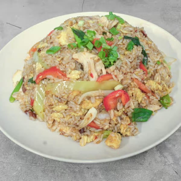 Thai Bliss fried rice with chicken, egg, red bell peppers, and green onions on a white plate.